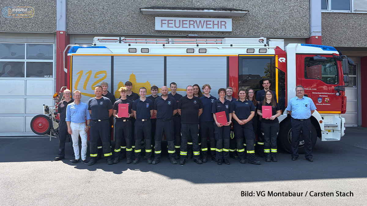 Gruppenfoto der neuen Feuerwehrfrauen und Feuerwehrmänner der VG Montabaur vor einem Feuerwehrfahrzeug und dem Feuerwehrgerätehaus. Mehrere Absolventinnen und Absolventen halten ihre Ernennungsurkunden in den Händen.